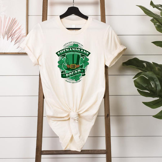 Shenanigans Squad T-Shirt with green St. Patrick’s Day design and knotted front hanging on wooden rack