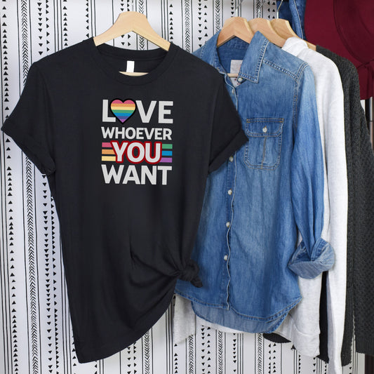 Black Love Whoever You Want T-shirt with rainbow heart and stripes promoting love and acceptance hanging alongside denim and other shirts