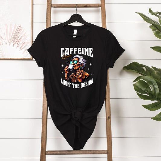 Caffeine Queen Livin' the Dream T-shirt hanging in black 